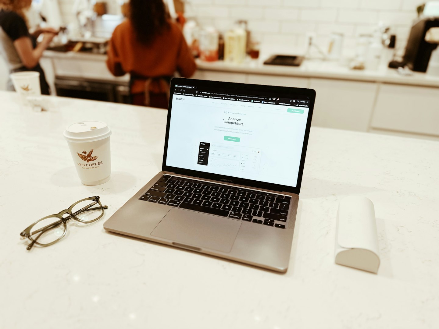 Laptop showing analytics dashboard and coffee on a white counter.